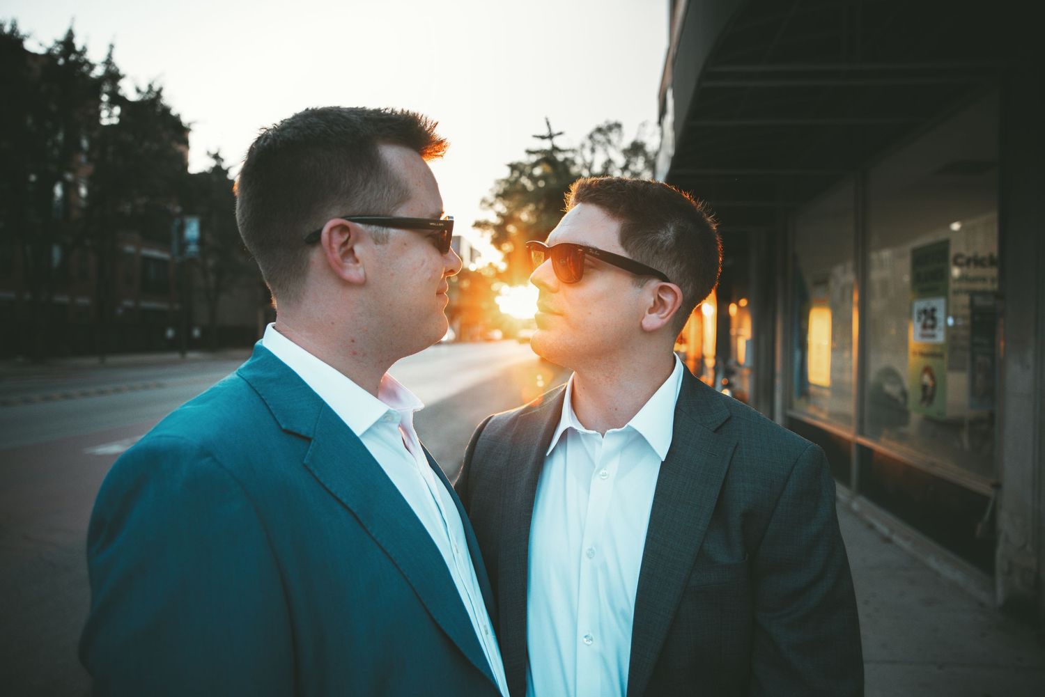 Two men in suits facing each other at sunset on a city street.