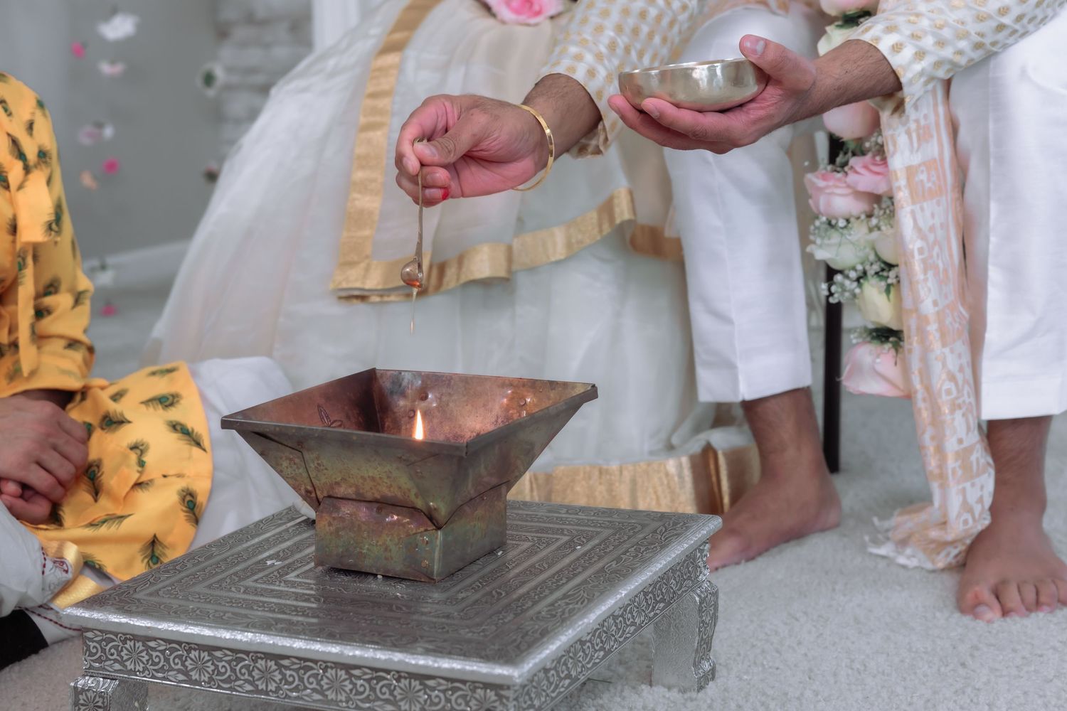 Hands perform sacred ritual over ceremonial fire during traditional Hindu wedding ceremony.