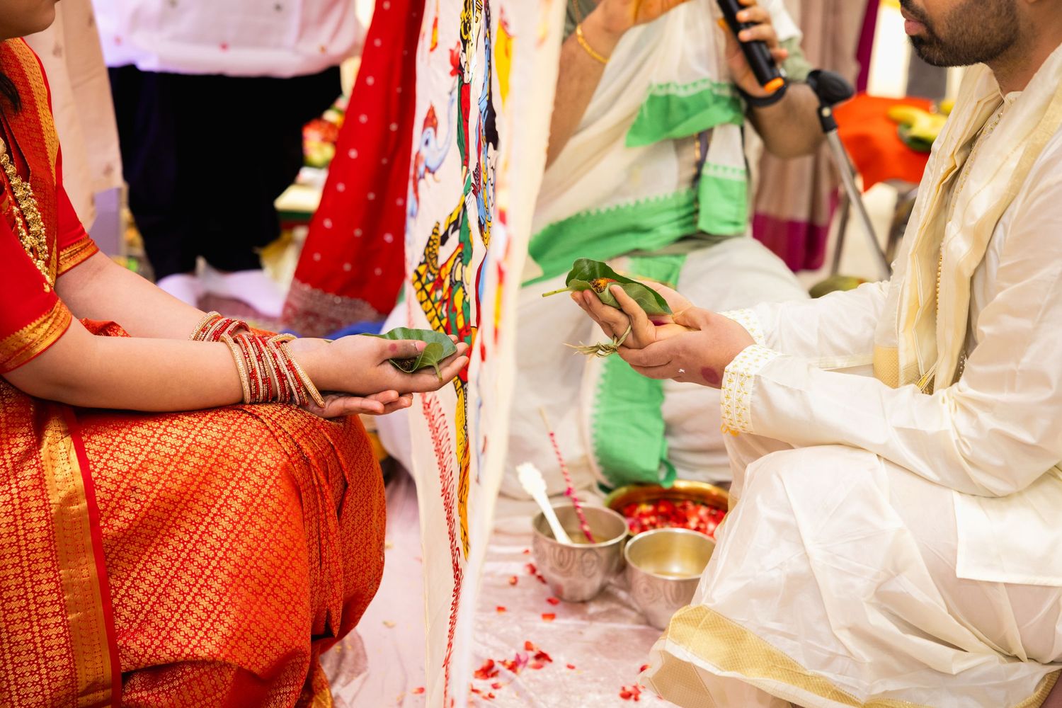 Close-up of Indian bride and groom exchanging ritual offerings during traditional Hindu wedding ceremony.