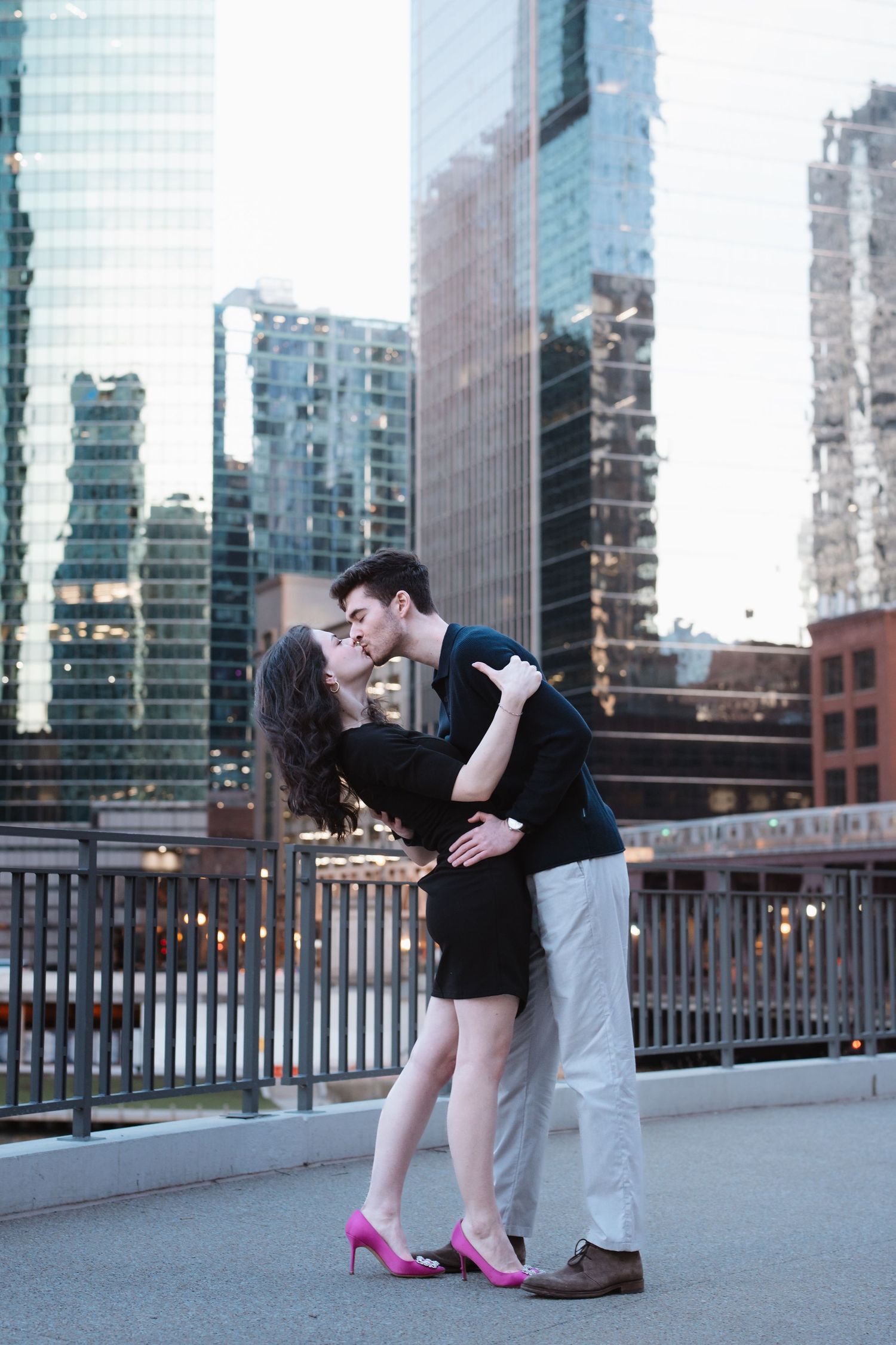 Couple sharing a passionate kiss with Chicago skyscrapers and elevated train in background.