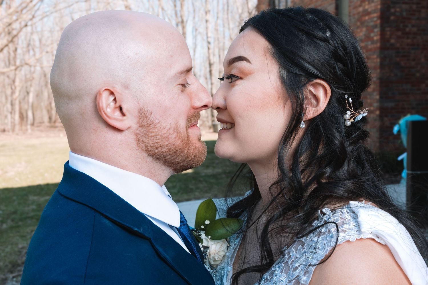 Bride and groom share a sweet nose-to-nose moment in close-up on their wedding day outdoors.
