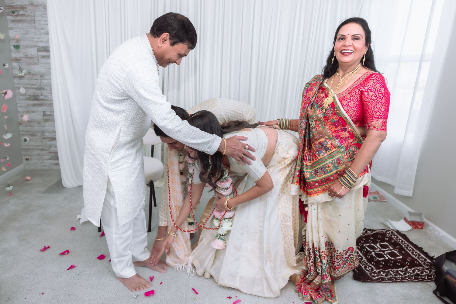 Traditional Indian wedding ritual with groom touching bride's feet as family members look on.