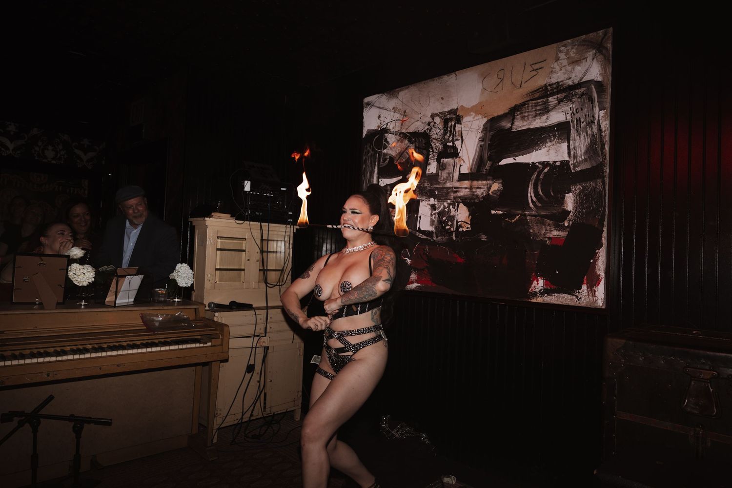 Fire dancer performer entertaining wedding guests at dramatic evening reception with vintage piano backdrop.
