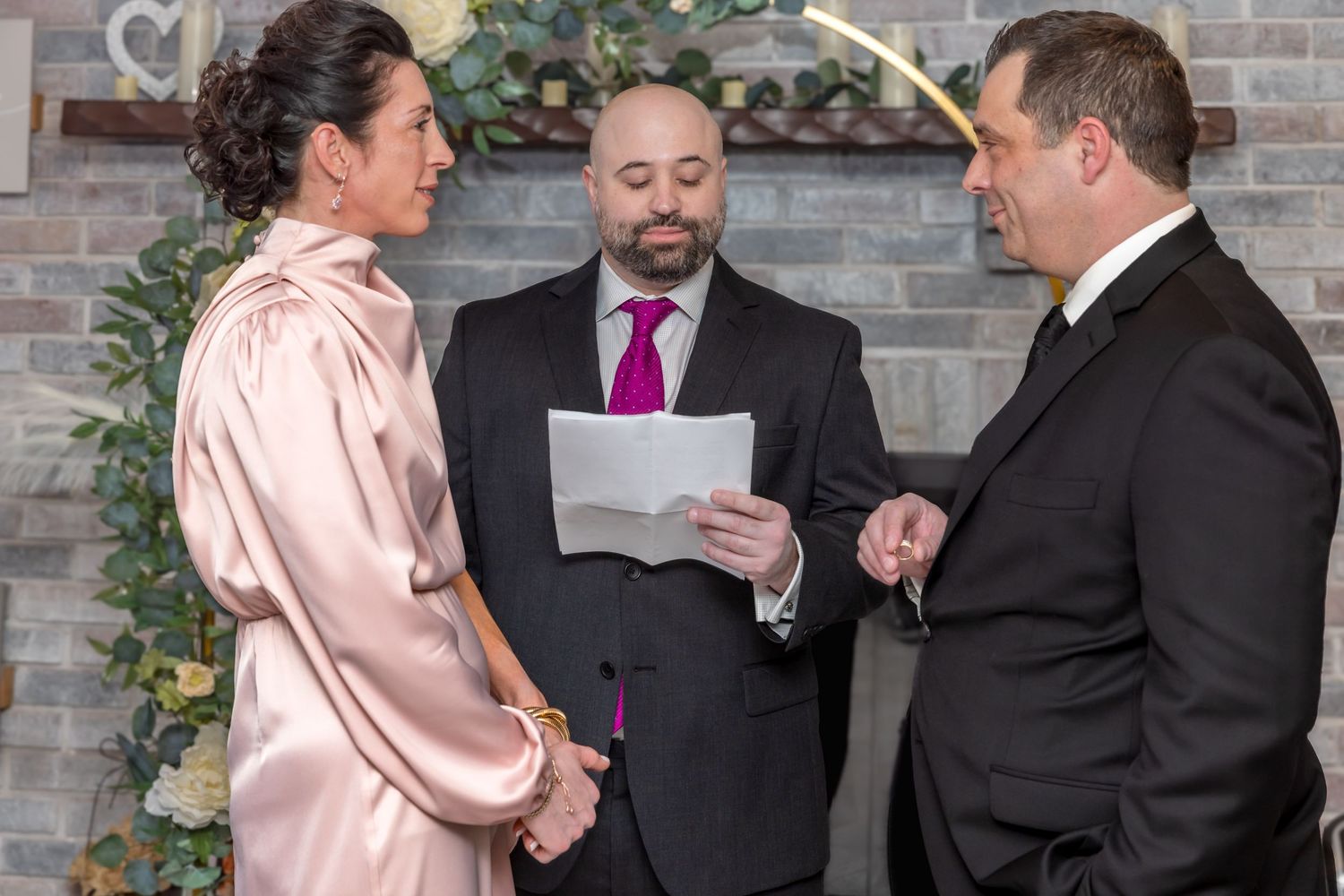 Wedding ceremony with couple exchanging vows before officiant in decorated indoor venue.