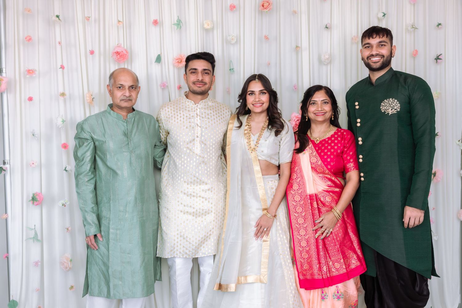 Family of five at Indian engagement, elders in green and pink saree with young men.