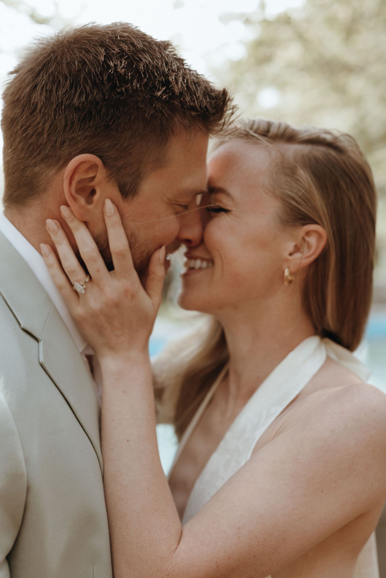 Bride and groom share a romantic nose-to-nose moment showing diamond engagement ring.