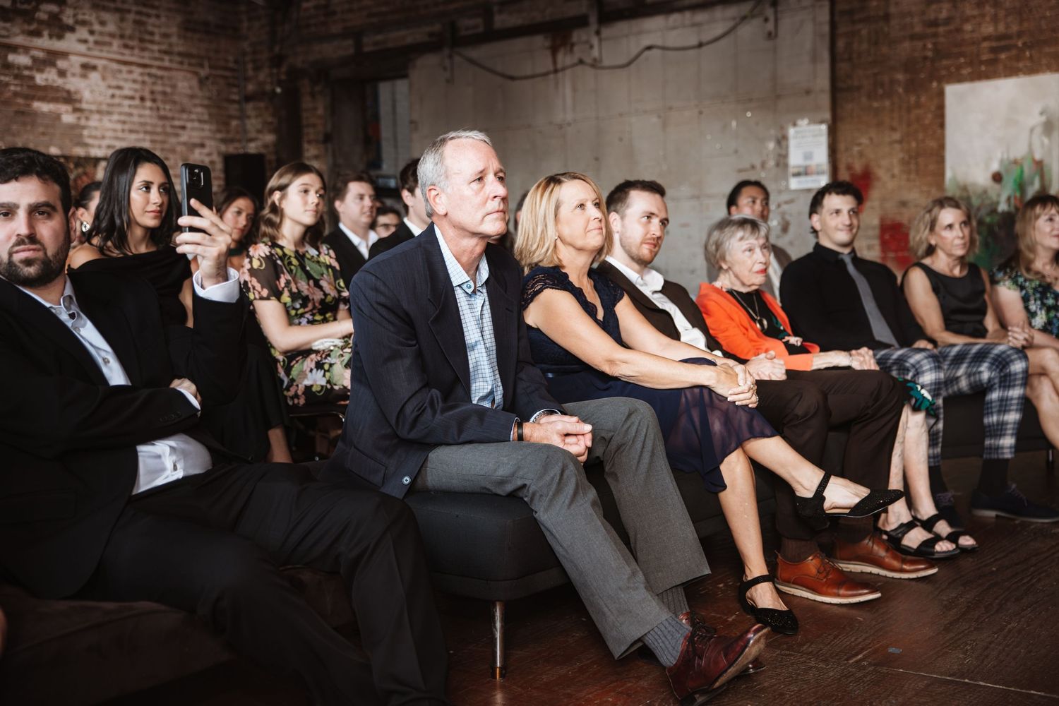 Wedding guests seated attentively in rows at an indoor ceremony venue.