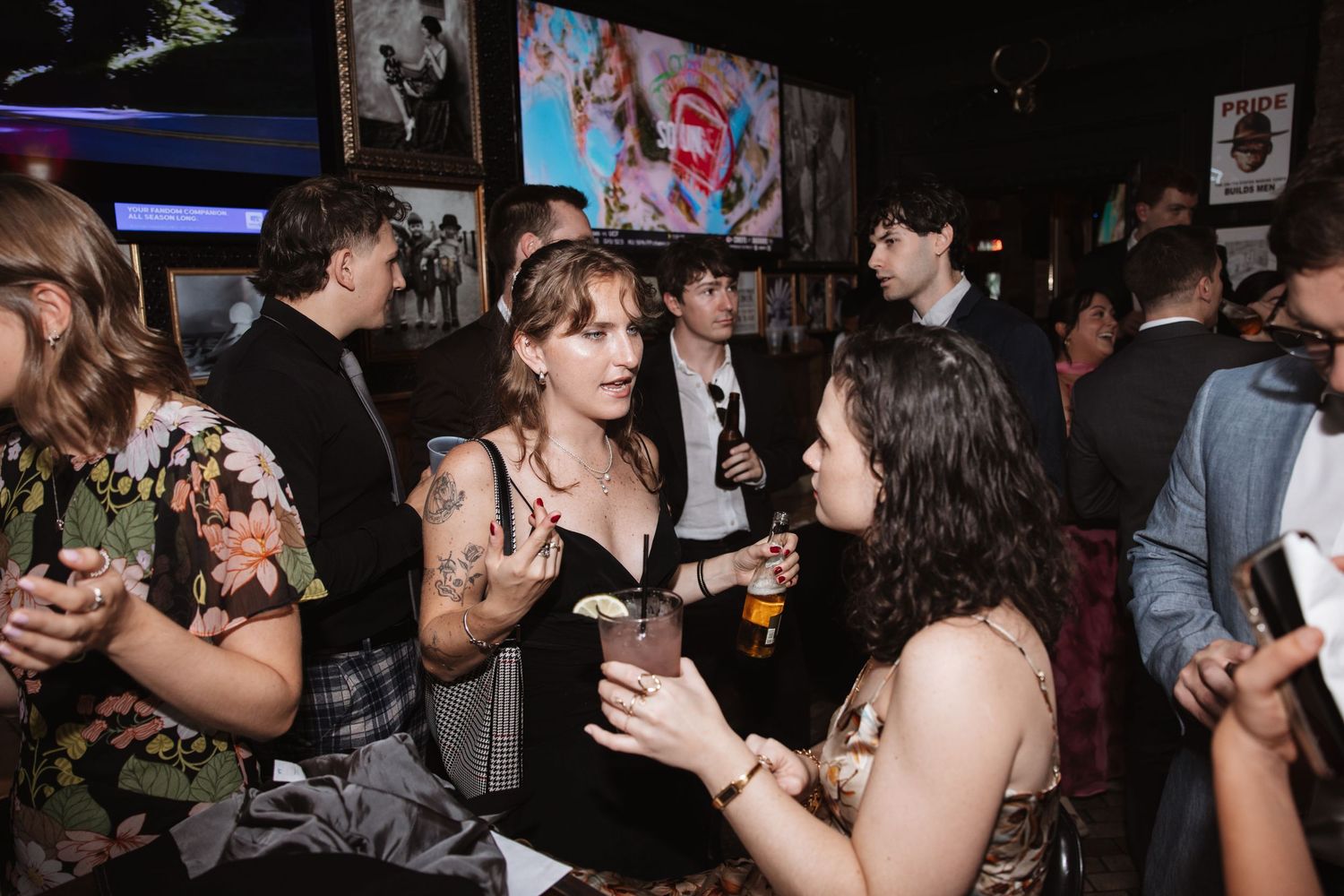 Guests mingling with drinks at a vibrant indoor wedding reception party.
