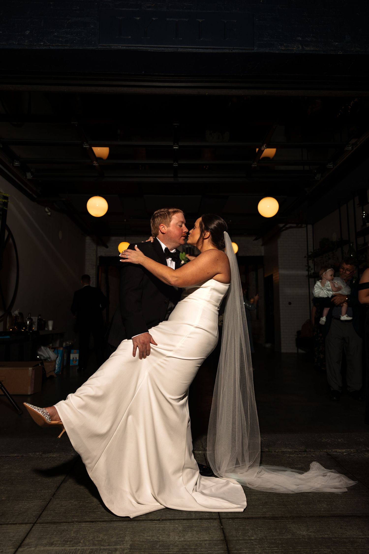 Groom dipping bride for a romantic kiss during their first dance at wedding.