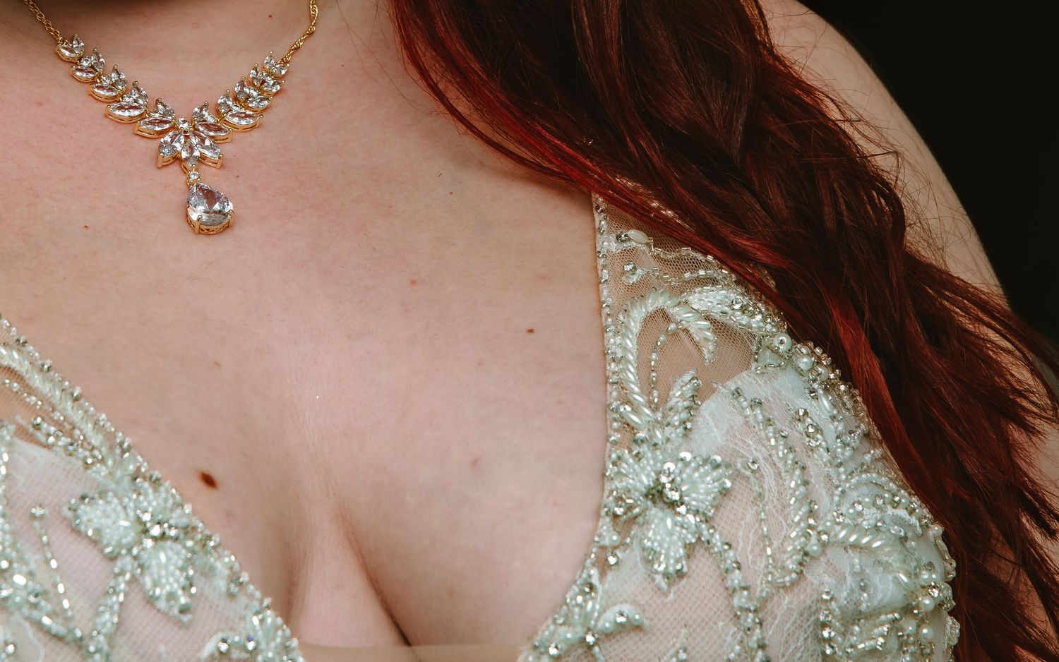 Close-up of a diamond necklace on a bride wearing an intricate beaded wedding dress.