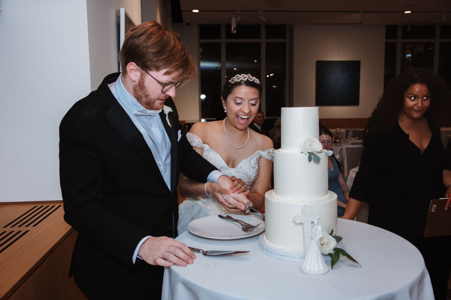 Bride and groom cutting their elegant white three-tier wedding cake at their reception.