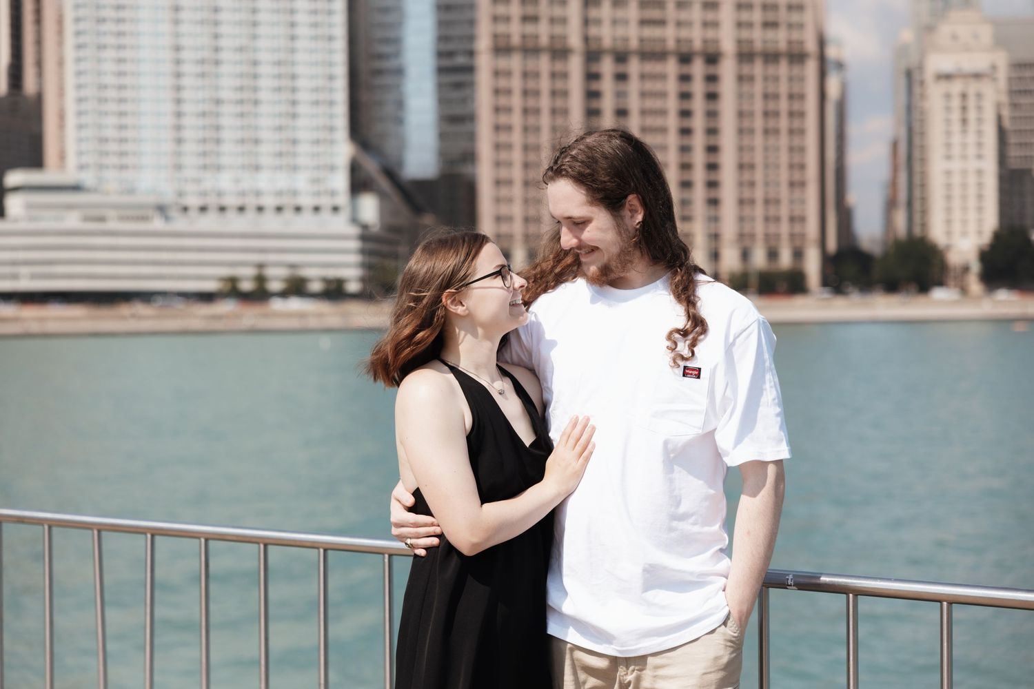 Young couple sharing a tender moment together with Chicago city skyline and river visible behind them outdoors.