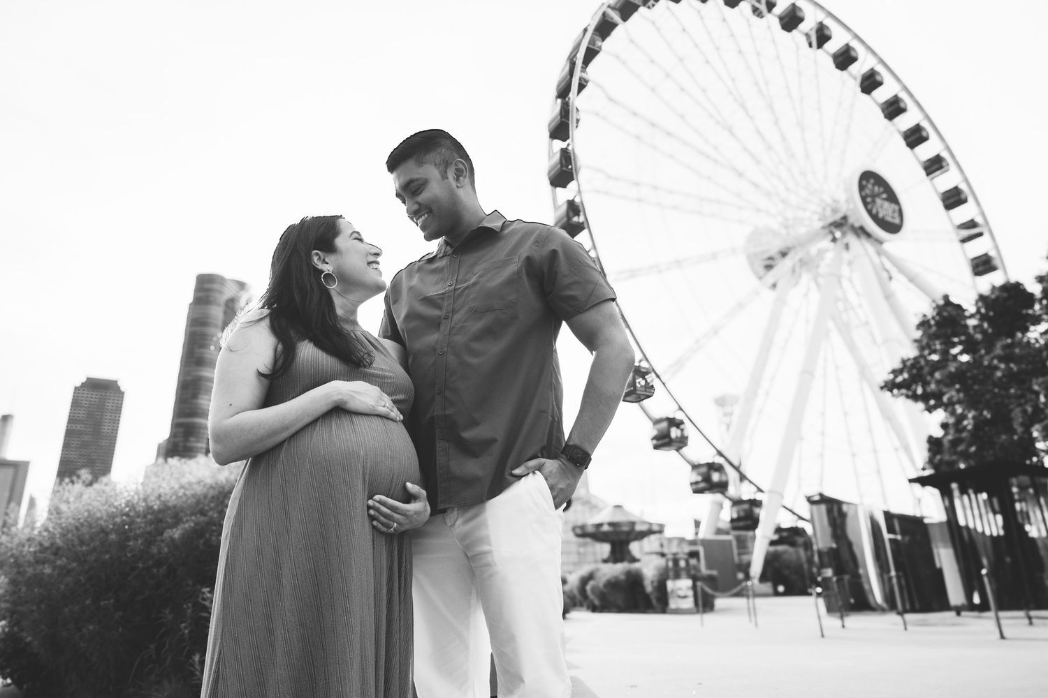 Black and white maternity photo of couple near Ferris wheel.