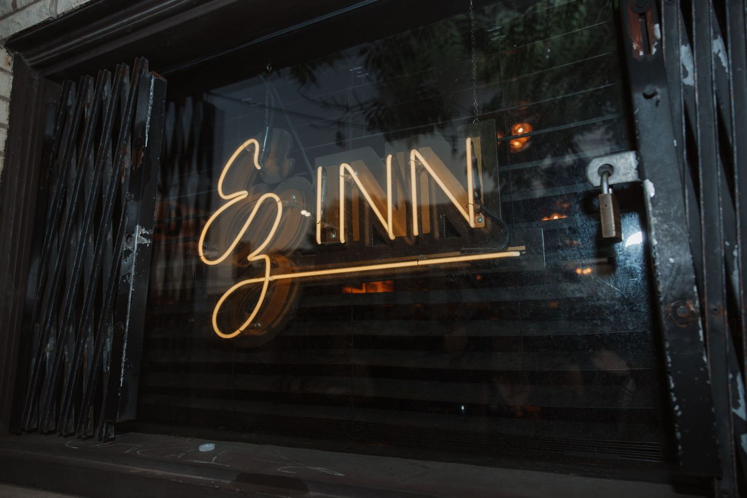 EZ Inn neon sign glowing in warm gold light displayed in a dark window storefront.