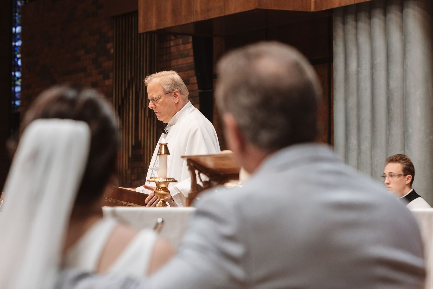 Priest reads from a book at the altar during a wedding ceremony in a church.