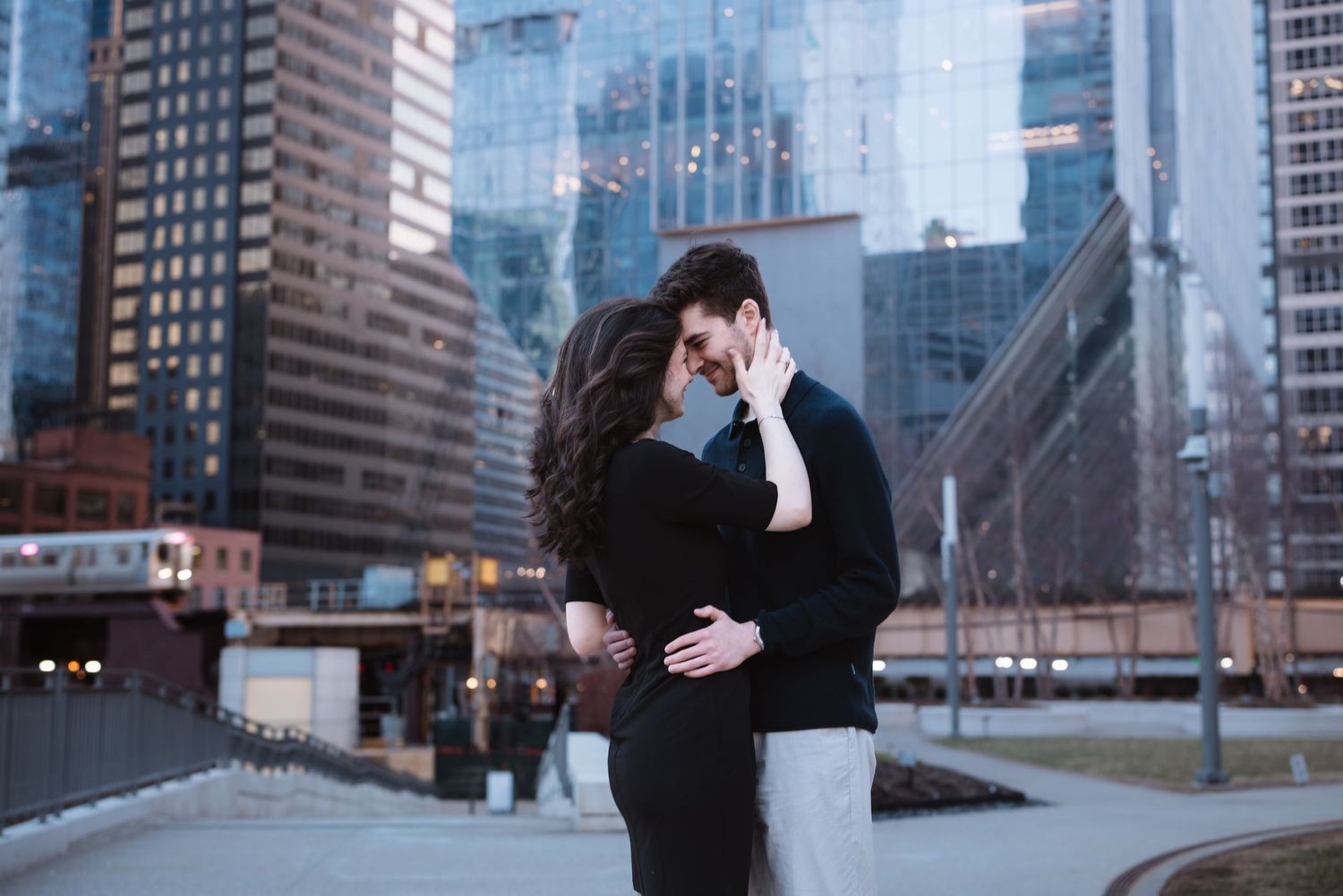 Romantic couple almost kissing in urban Chicago setting with glass skyscrapers in background.