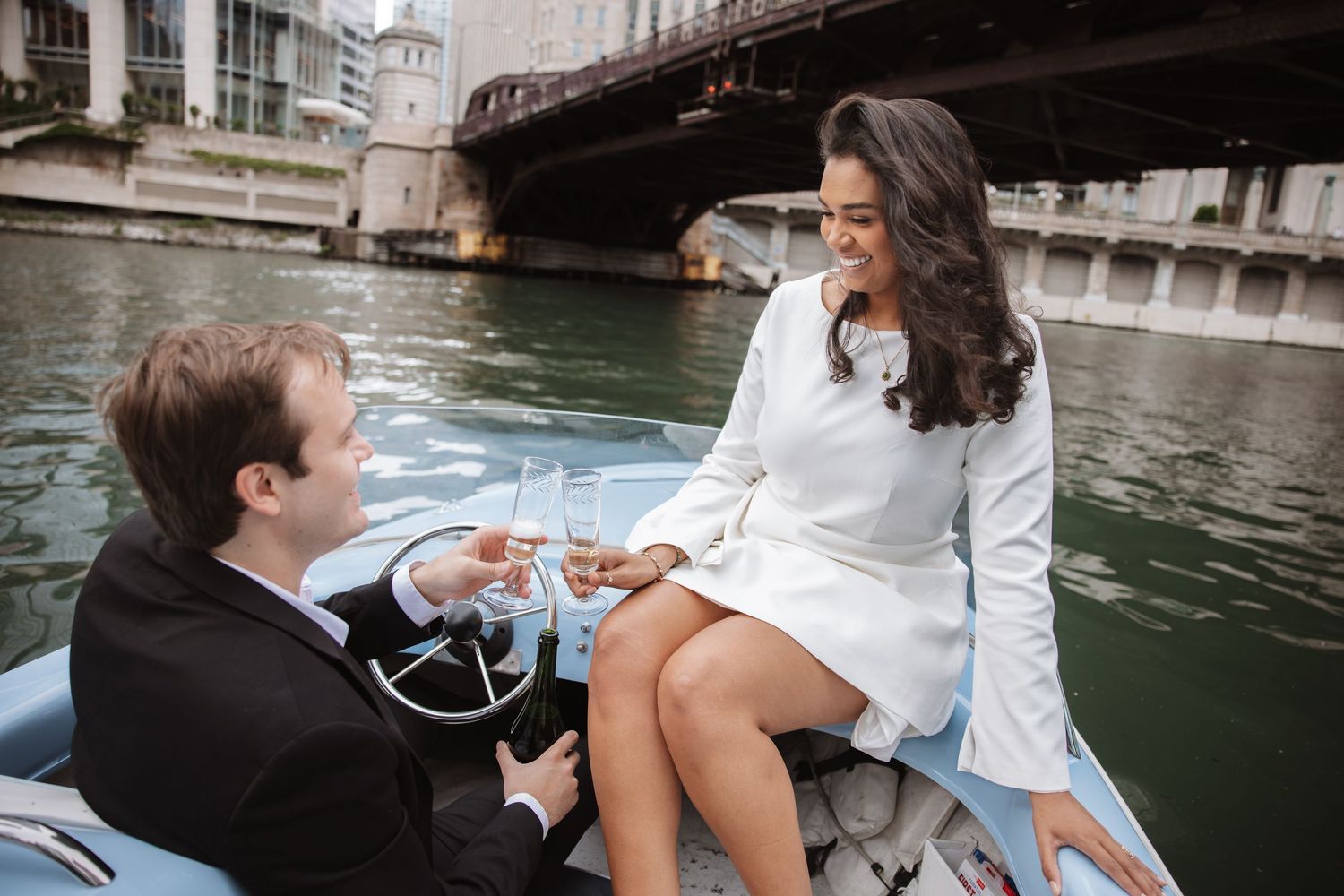 Elegant couple toasting champagne glasses on a classic blue boat along the Chicago River.