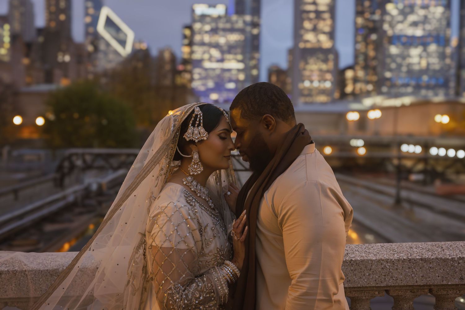 Bride and groom share romantic moment with Chicago city lights glowing behind them at dusk.