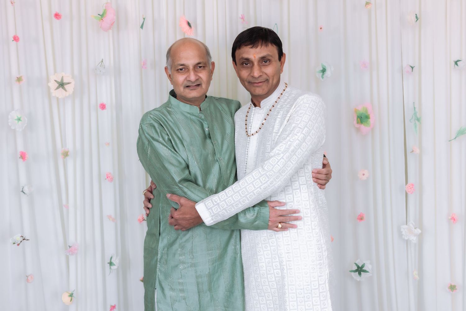 Two men in traditional Indian attire embracing warmly at festive celebration.