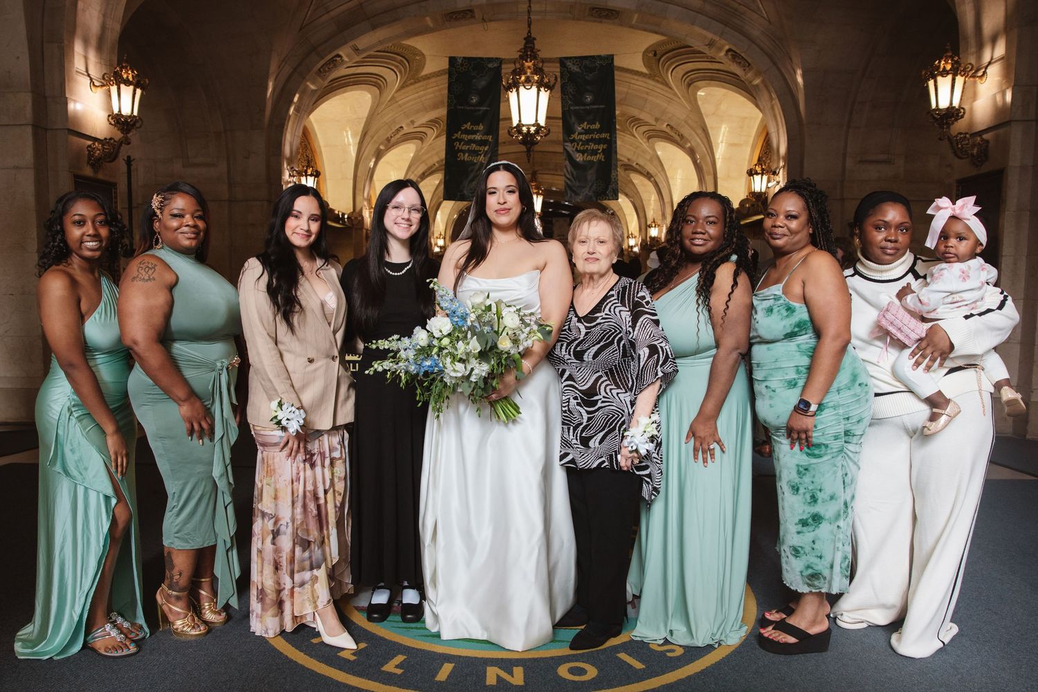 Bride poses with wedding party in mint green dresses at elegant Illinois venue with arched ceilings.