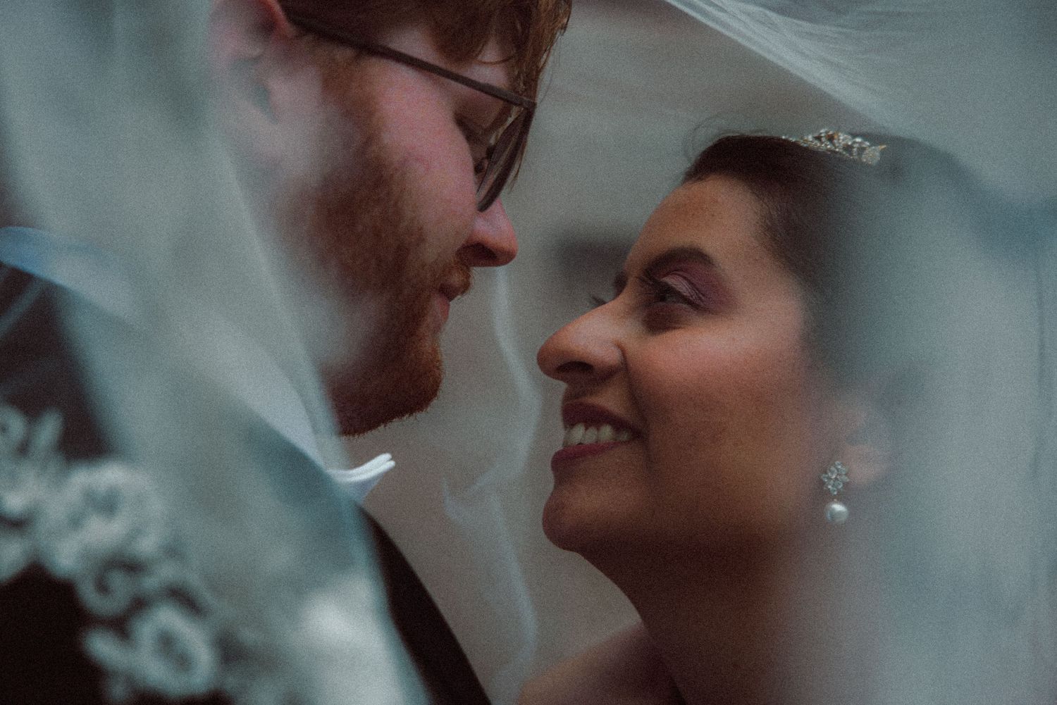 Intimate close-up of bride and groom gazing at each other beneath a flowing veil.