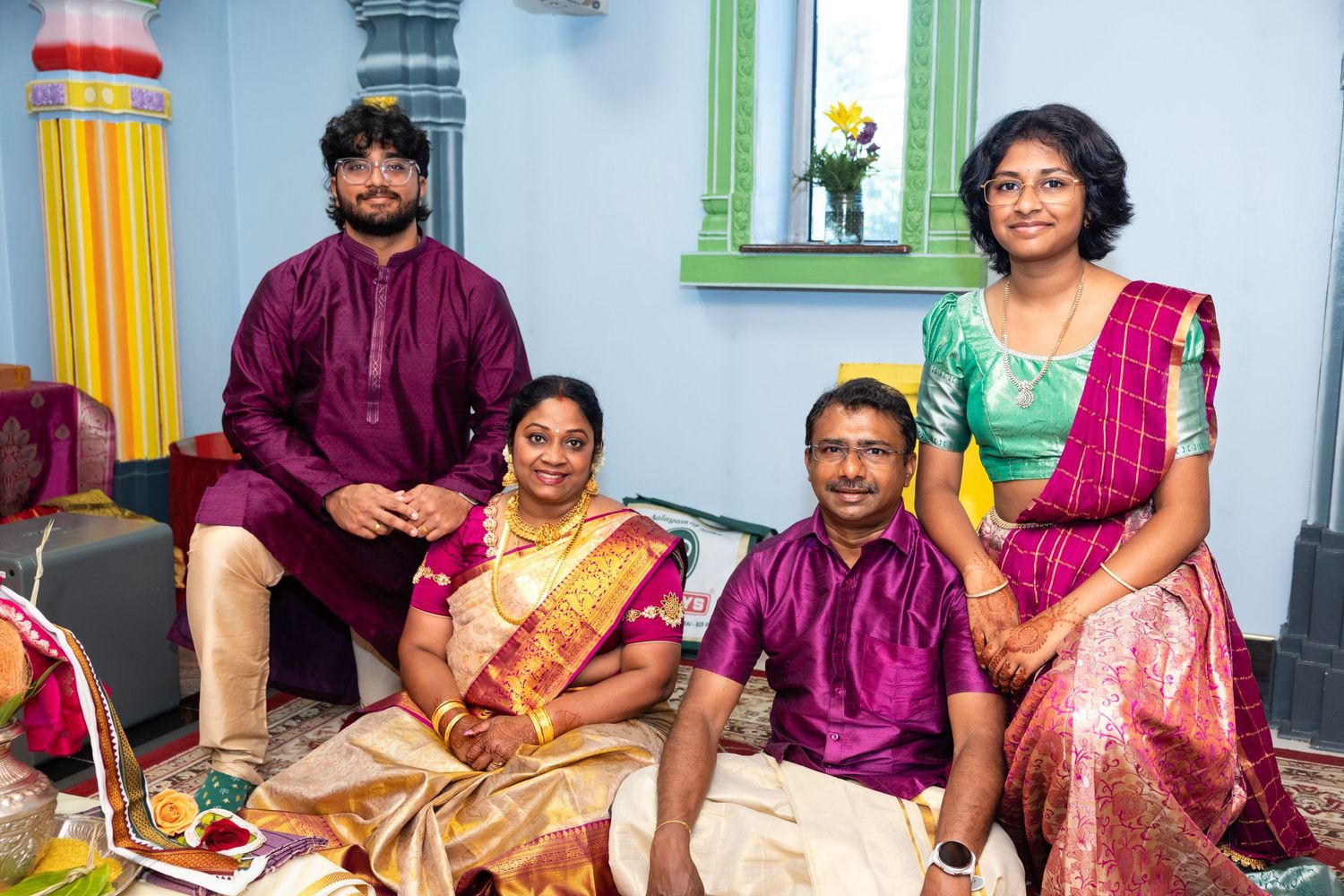 South Indian family in traditional silk attire posing together during a Hindu celebration ceremony.