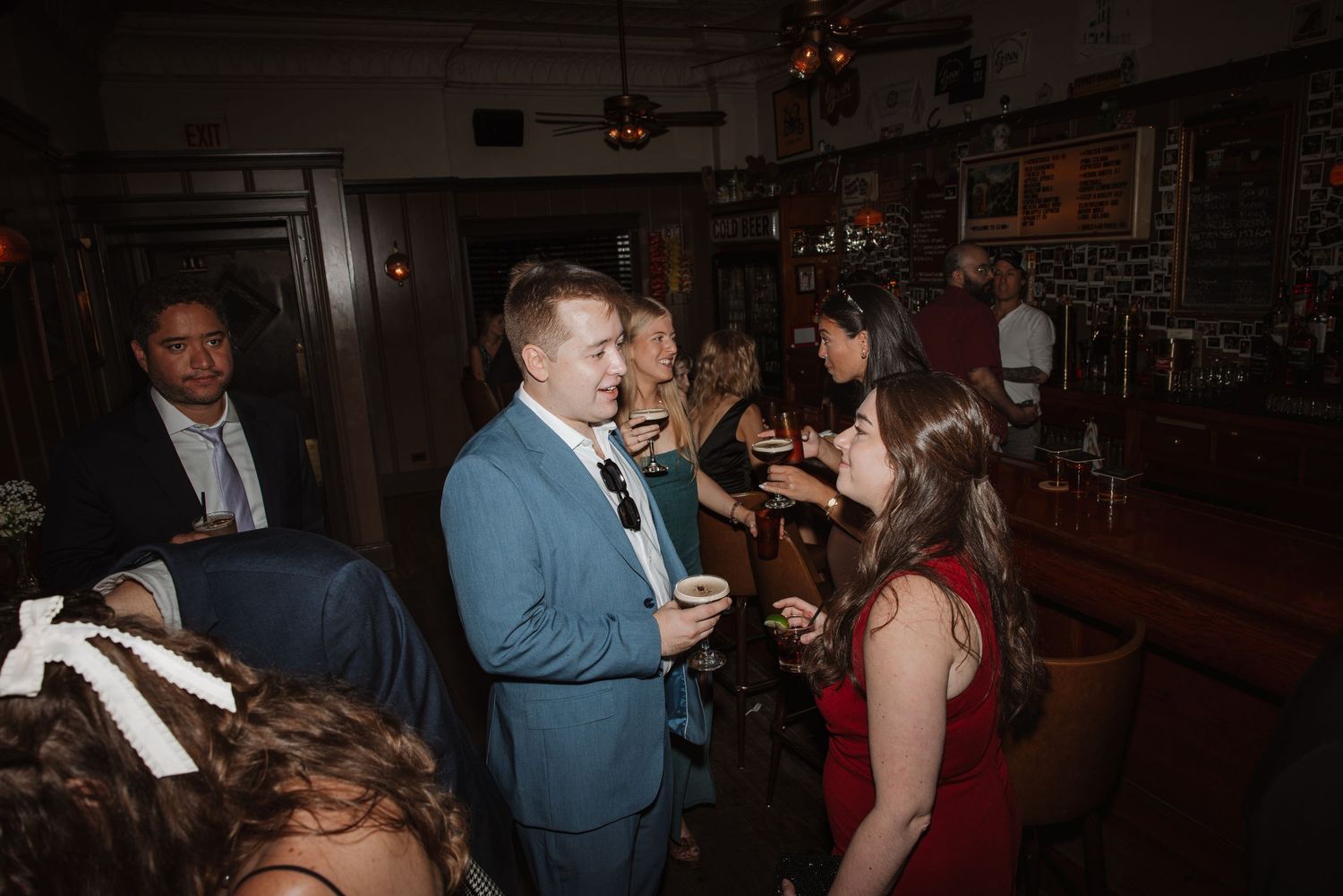 Guests socializing at a wedding reception in a warmly lit bar venue.
