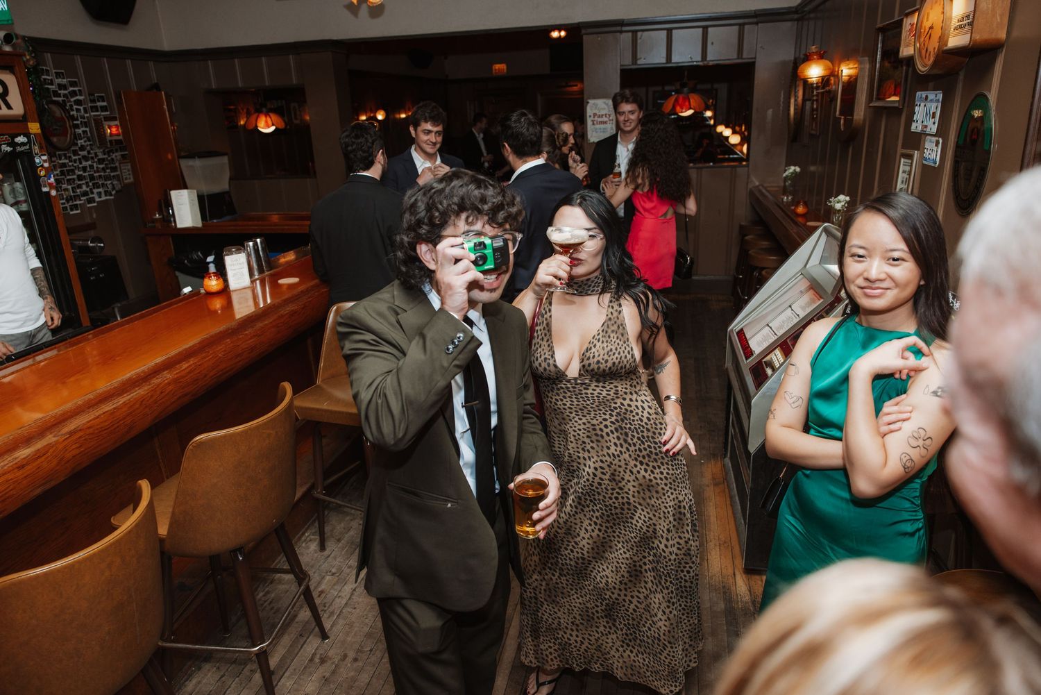 Wedding guests having fun with novelty glasses and drinks at a bar reception venue.