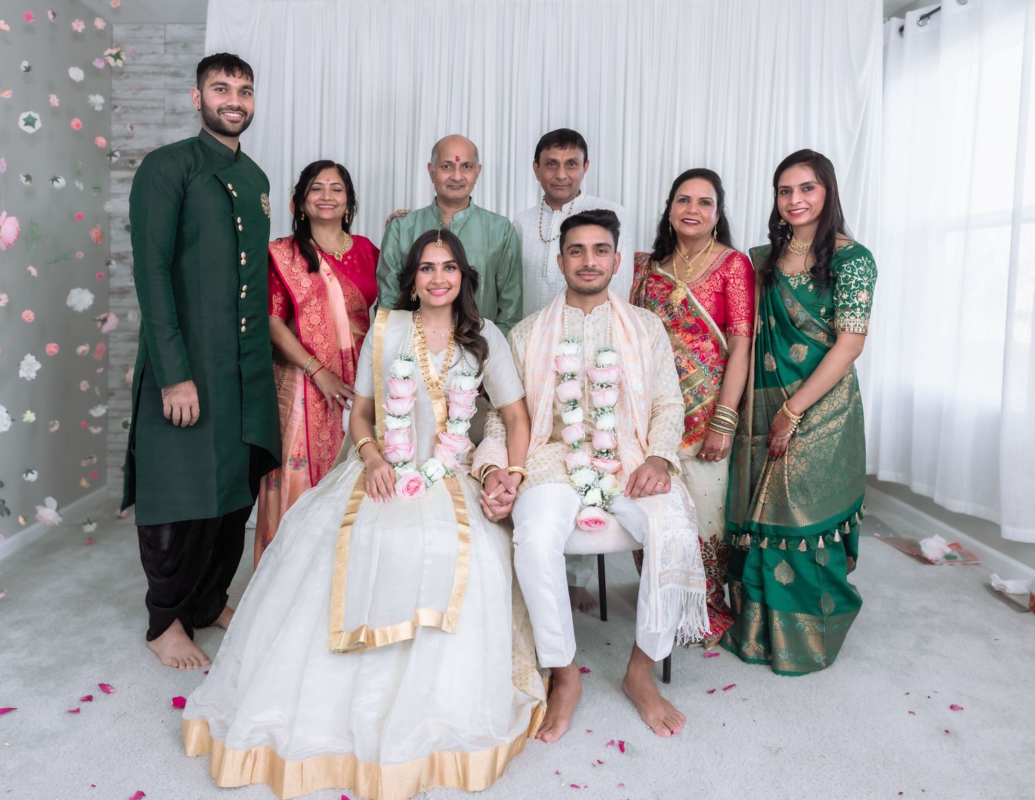 Indian wedding family portrait with bride and groom seated surrounded by relatives in festive attire.