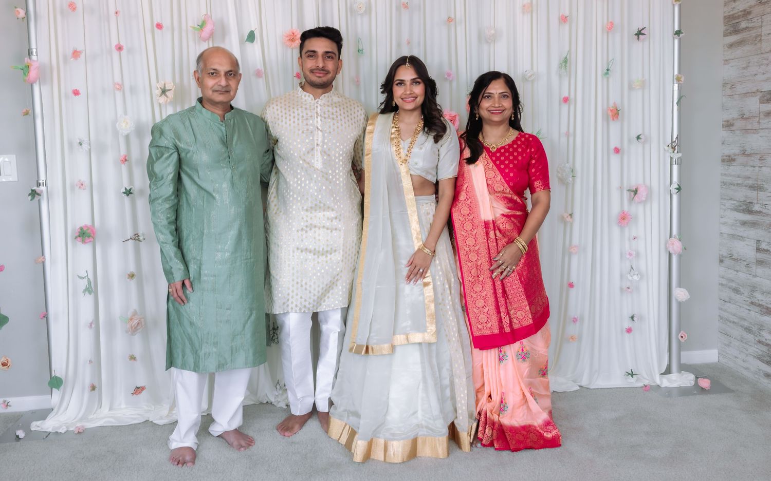 Indian wedding family portrait with bride in white lehenga and groom in cream sherwani with parents.
