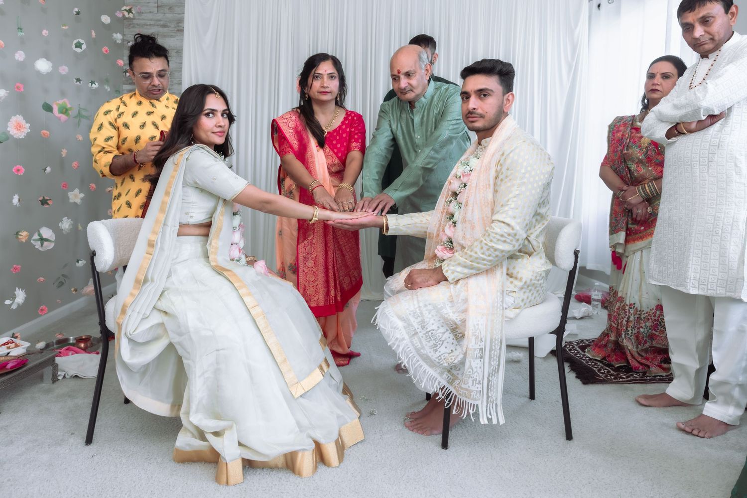 Indian wedding ceremony with family gathered as bride and groom perform traditional hand-joining ritual.