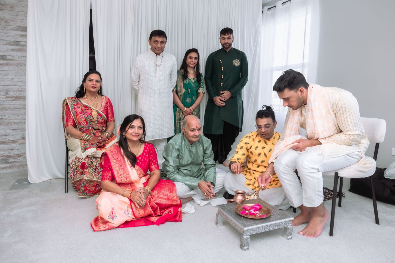 Indian family gathers for traditional Hindu wedding ceremony with bride in red saree and groom in white.