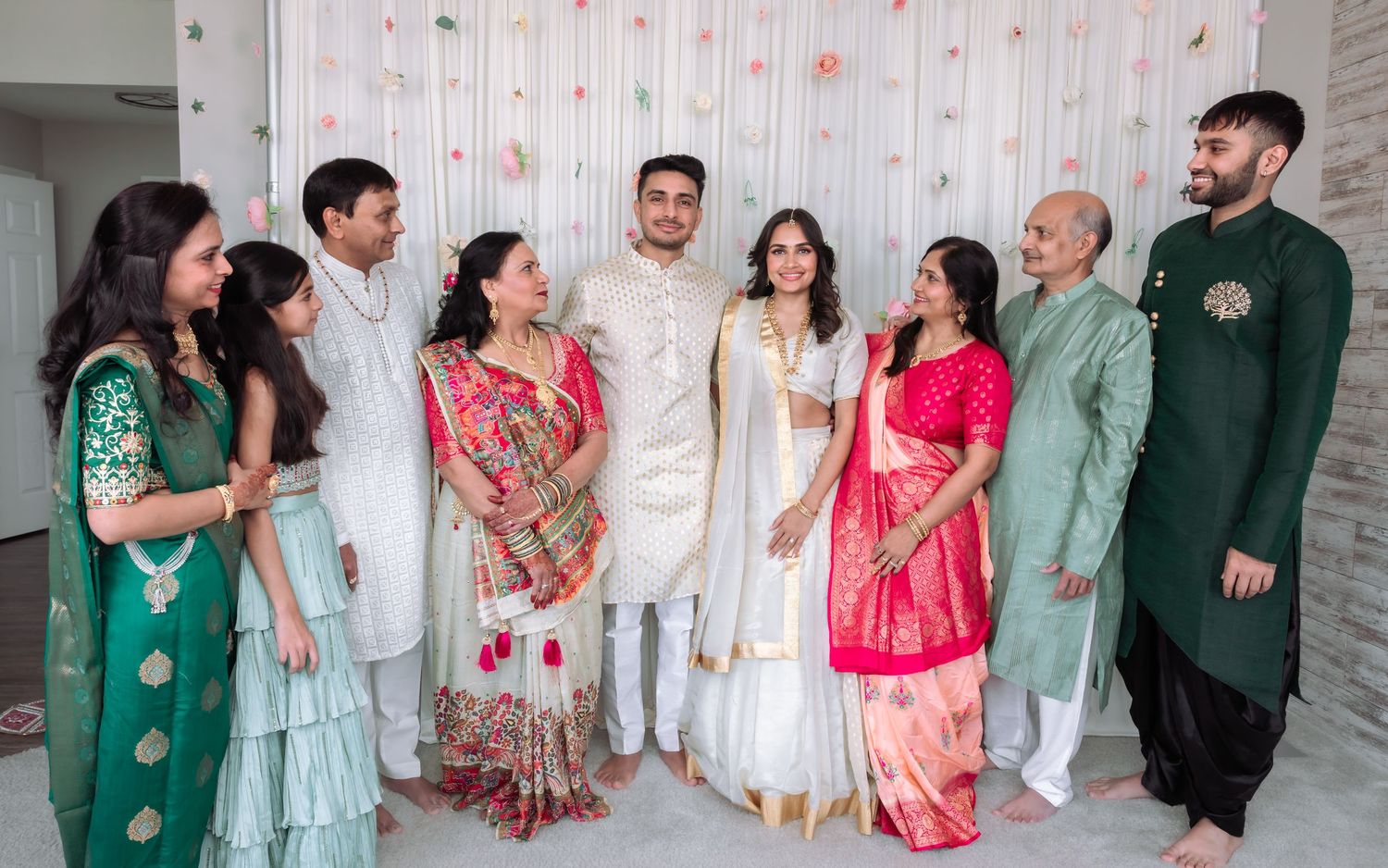 Extended family group photo in colorful traditional Indian wedding attire at a ceremony.