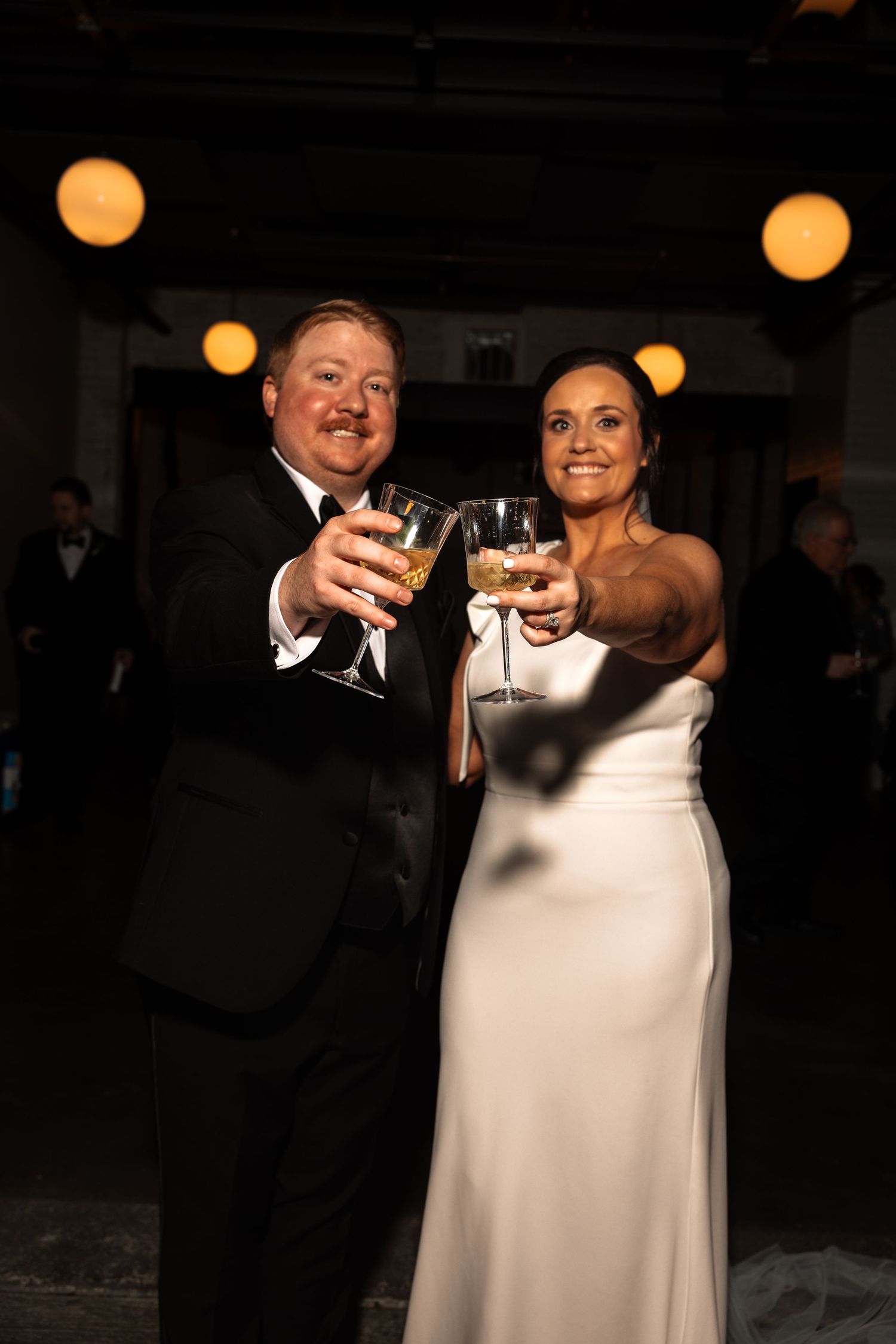Bride and groom smiling and toasting with champagne glasses at their wedding reception.