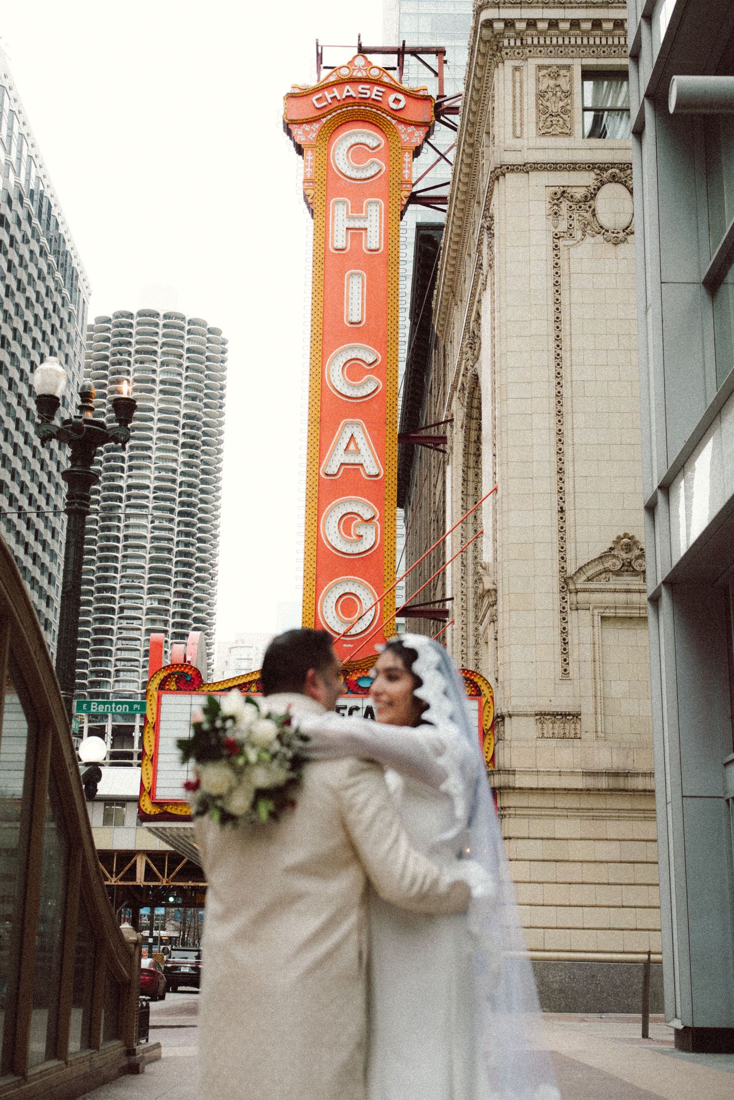 Bride and groom sharing a romantic embrace in front of the Chicago Theatre neon sign.