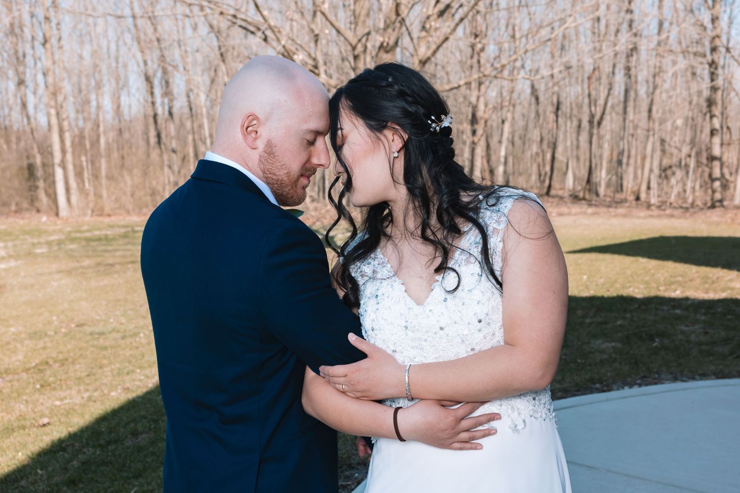Bride and groom sharing an intimate forehead-to-forehead moment outdoors.