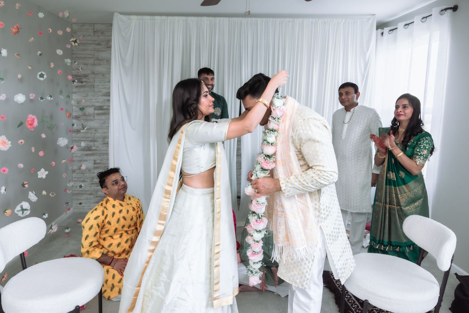 Bride places a floral garland on the groom during a traditional Indian Varmala wedding ceremony.
