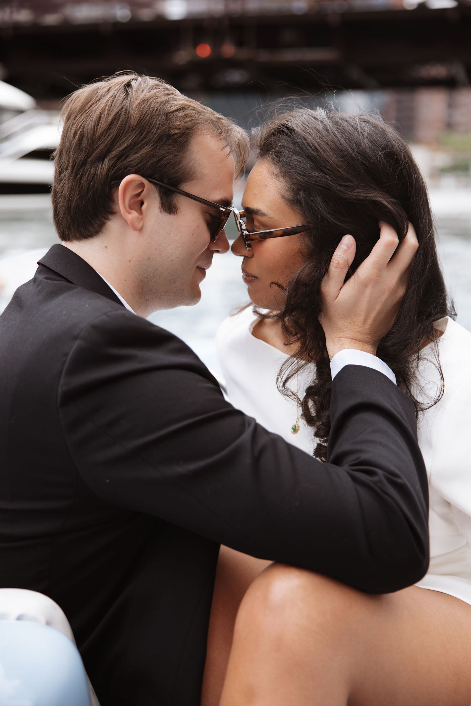 Romantic couple in sunglasses leaning in close together on a vintage blue boat on the Chicago River.