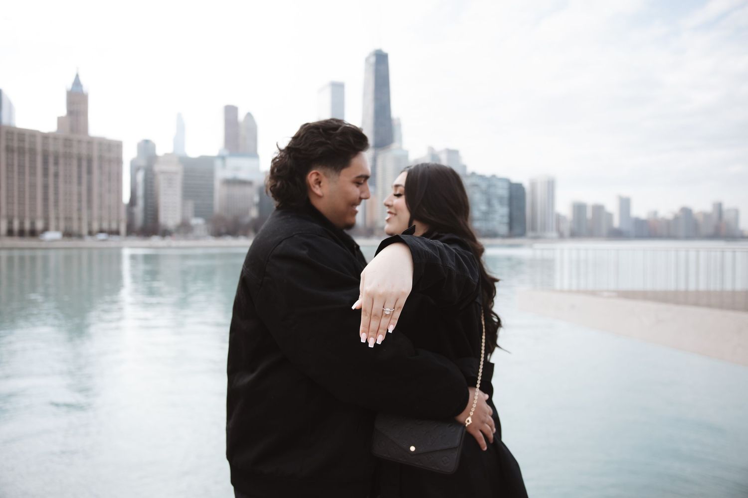 Couple embracing and about to kiss with the iconic Chicago skyline and blue water behind them.