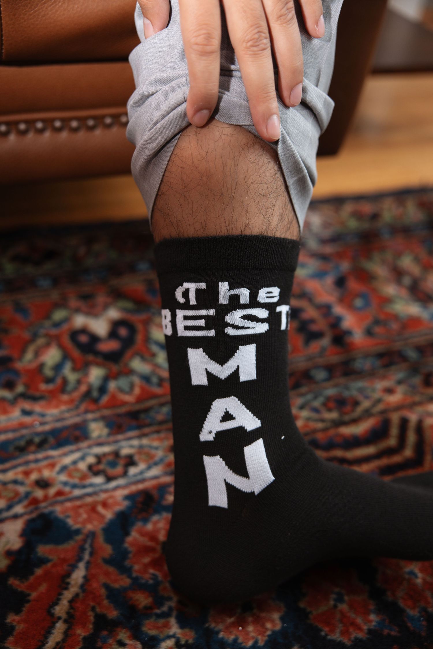 Best man wearing custom black socks with white THE BEST MAN text during wedding day getting ready.