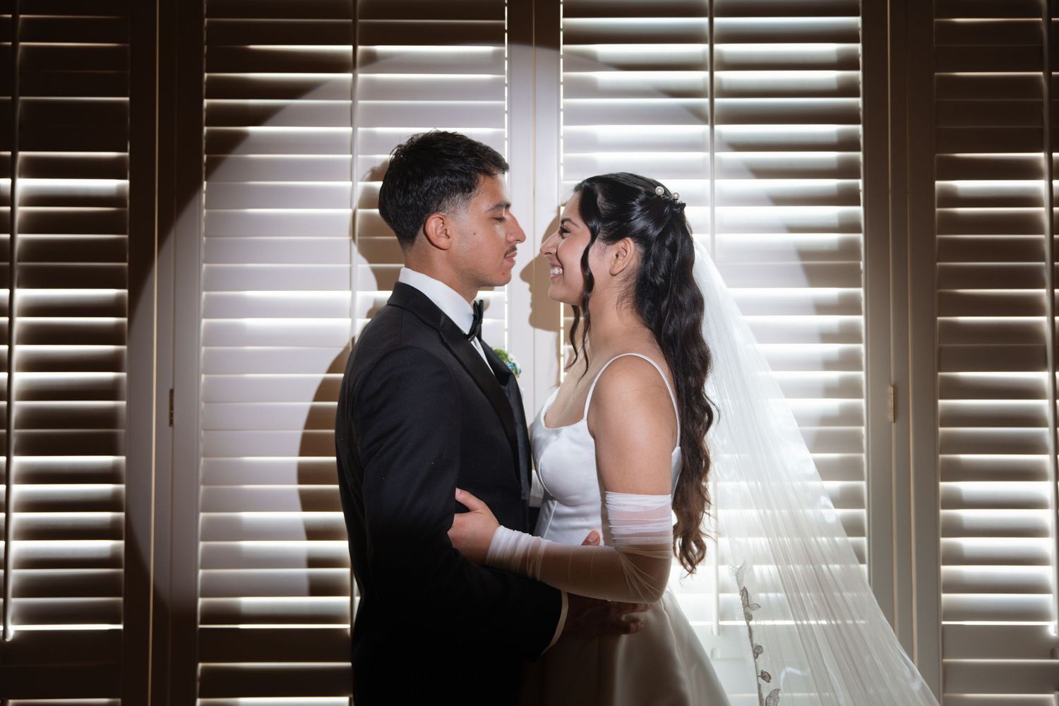 Bride and groom gazing into each other's eyes in a romantic moment bathed in natural light.