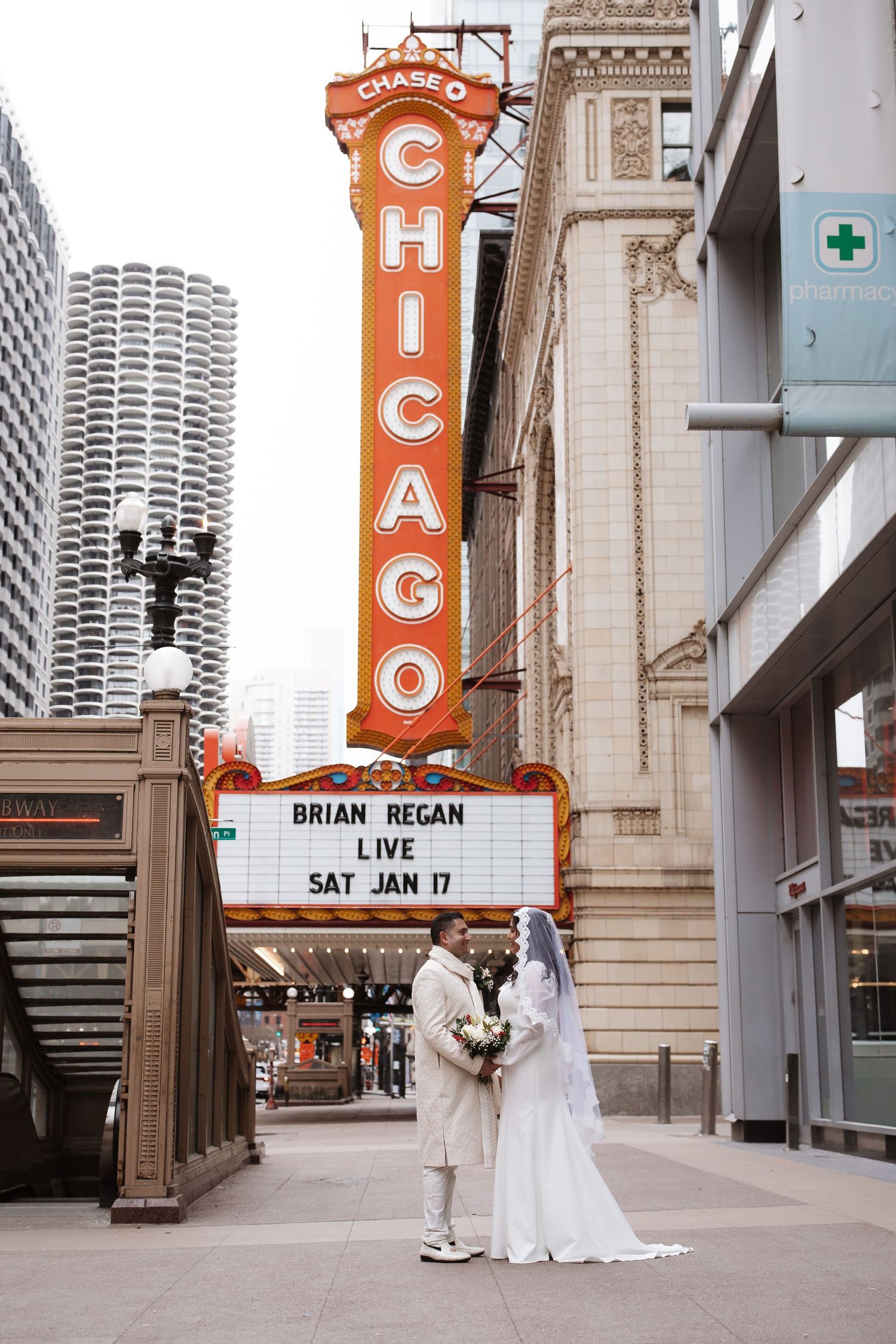 Bride and groom posing in front of the iconic Chicago Theatre marquee on their winter wedding day.