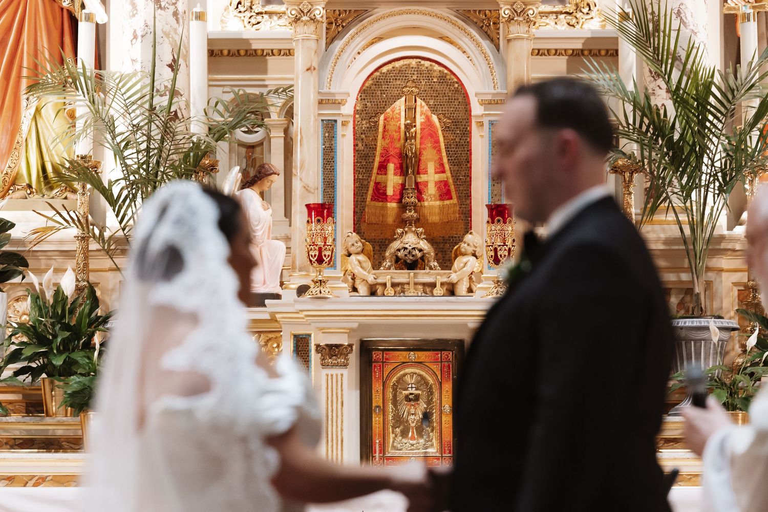 Bride and groom stand at ornate church altar during Catholic wedding ceremony.