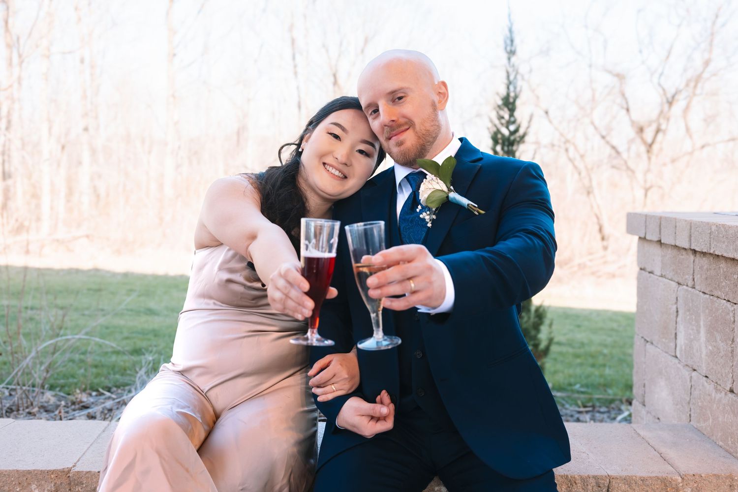 Bride and groom toasting with red wine glasses outdoors at their wedding celebration.