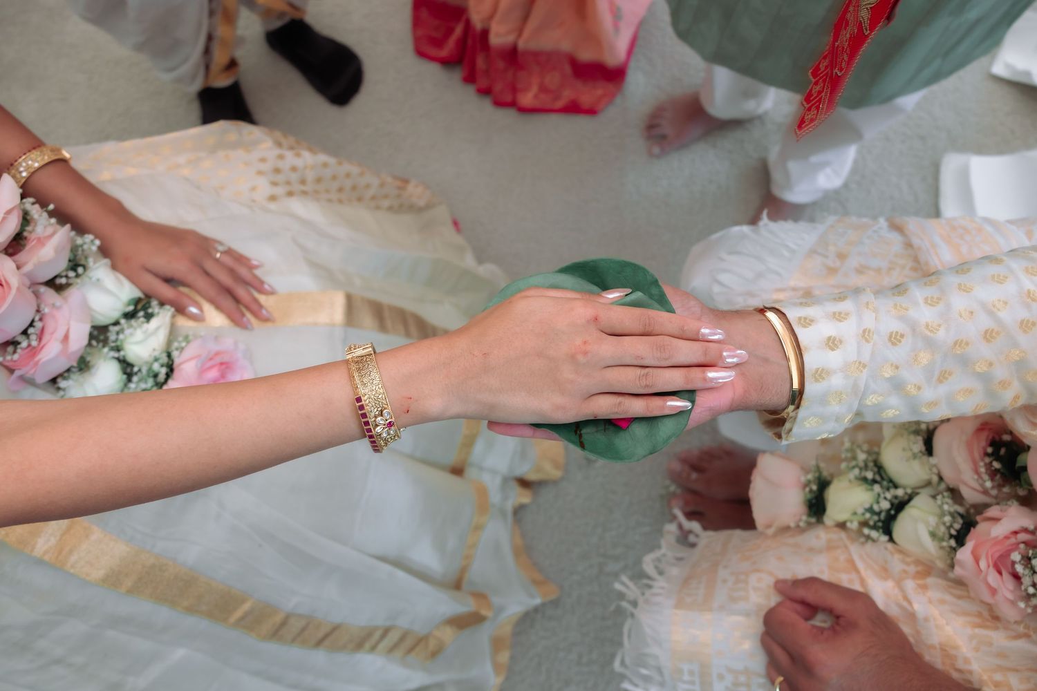 Close-up of bride's hands adorned with gold bangles during a traditional South Asian wedding ceremony ritual.
