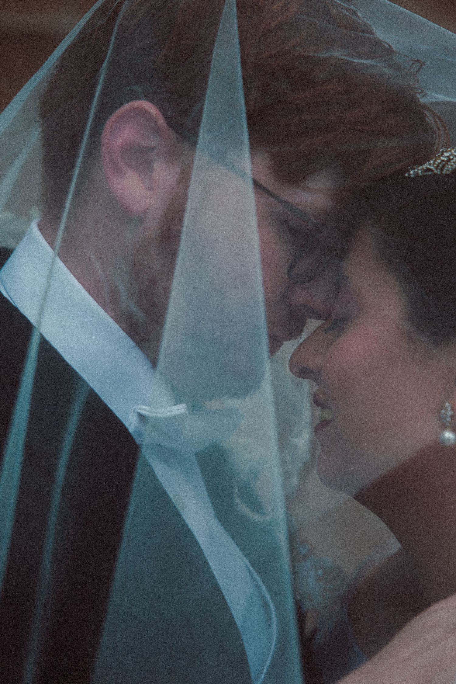 Bride and groom sharing an intimate moment under a lace-trimmed wedding veil.