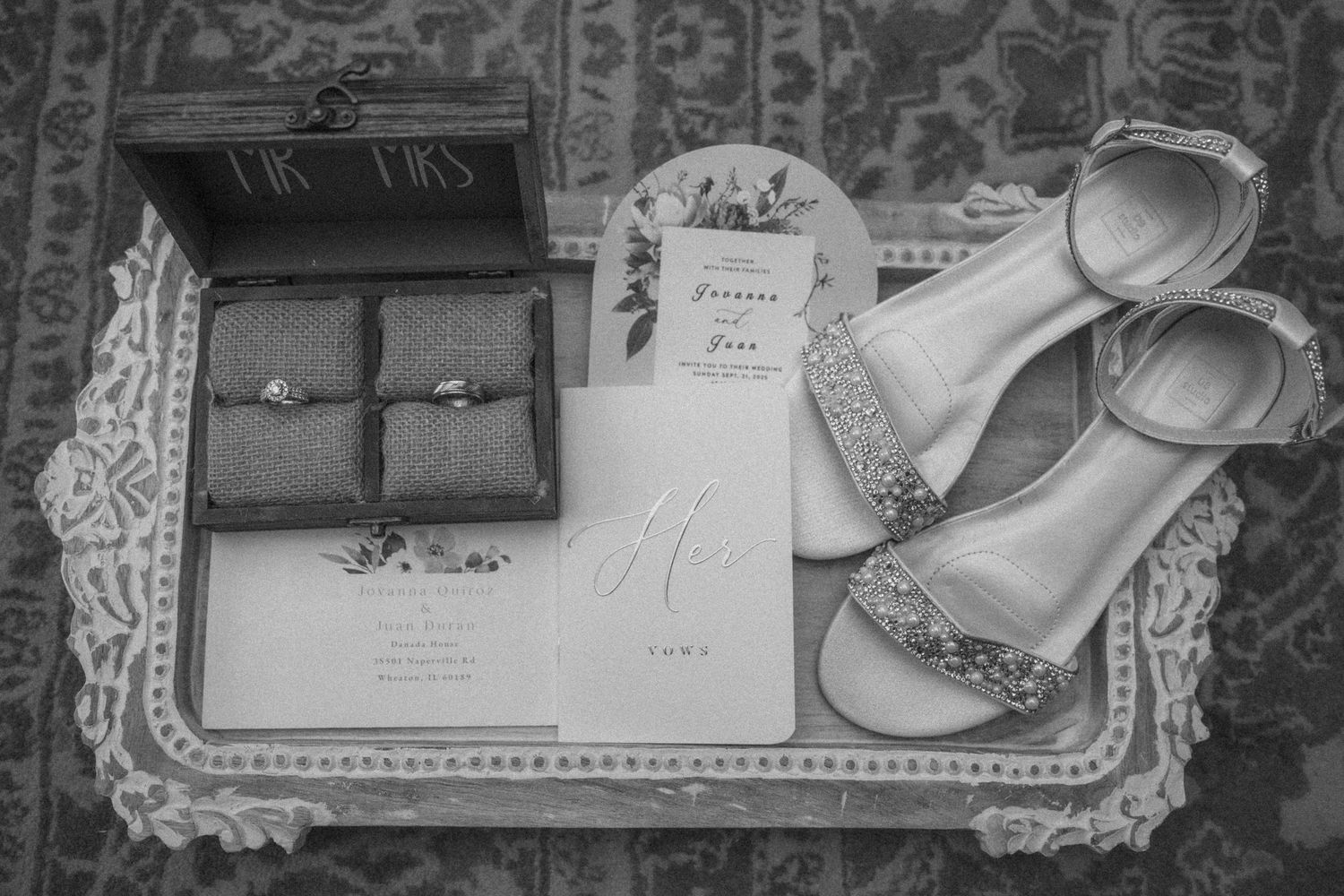 Black and white flat lay of wedding rings in Mr and Mrs box with invitation and bridal heels.