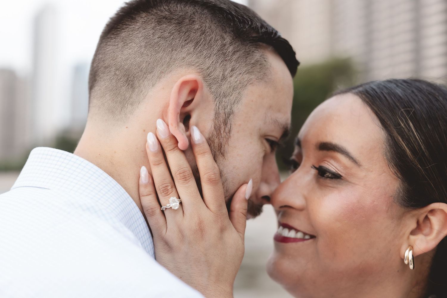 Close-up of engaged couple touching foreheads, woman showing diamond engagement ring on her hand.