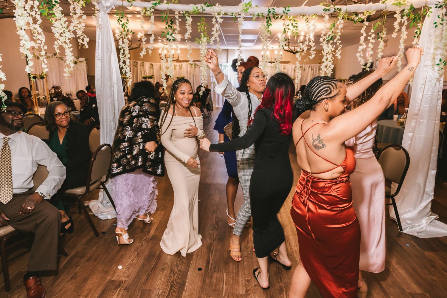 Wedding guests dance joyfully on the dance floor during a lively indoor wedding reception.