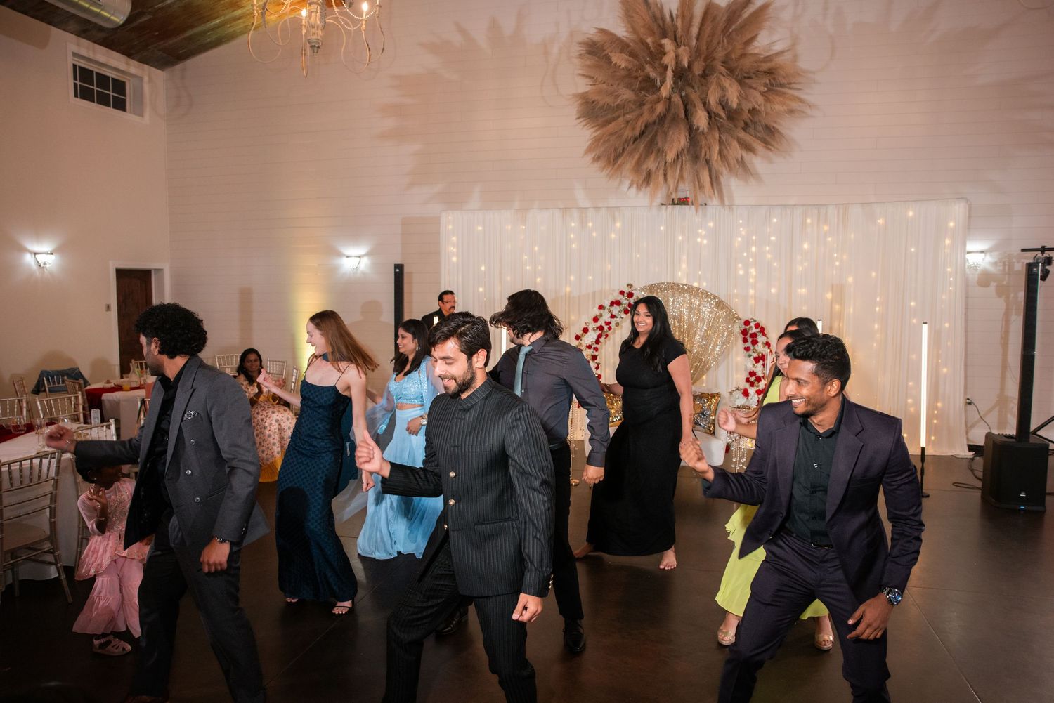 Wedding guests enjoying a lively dance floor at an elegant indoor reception venue.
